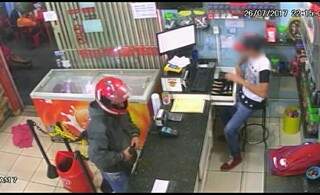 Nas imagens é possível ver os clientes ao fundo e o bandido rende funcionário. (Foto: JP News/ Divulgação)