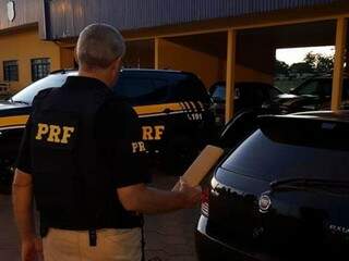 Policial segura tablete de maconha apreendido com suspeito. (Foto: PRF) 