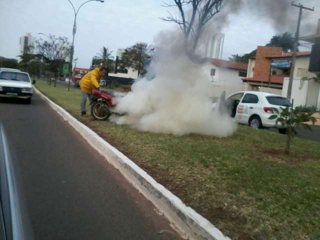 Motocicleta pega fogo na Via Parque e motoristas ajudam a apagar chamas