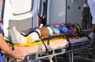 Felipinho, do Ivinhema, sendo levado de ambulância. Ele fraturou a perna esquerda em dividida de bola com o goleiro do Novoperário (Foto: Alcides Neto)
