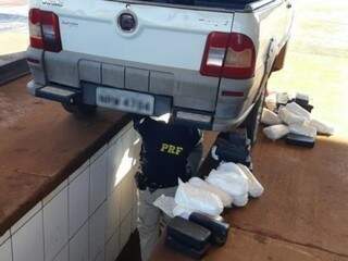Policial retirando a droga do fundo falso do veículo. (Foto: Divulgação/PRF) 