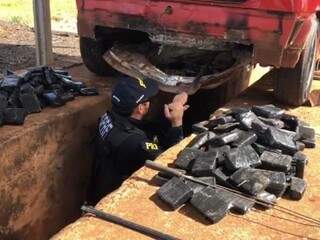 Policial retirando os tabletes de droga encontrados sob a lataria do Gol. (Foto: Divulgação/PRF) 