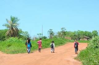 A pé, alunos vão e voltam da escola na aldeia. 