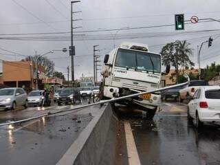 Caminhão em cima de mureta e poste caído na via (Foto: Henrique Kawaminami)