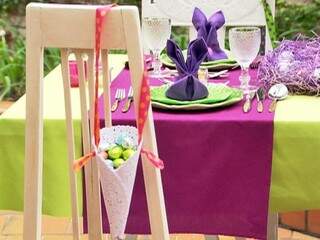 Cone com ovinhos de chocolate e uma mesa super colorida no jardim.