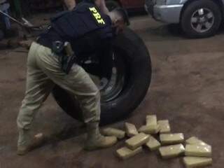 Policial retirando tabletes de cocaína do estepe onde estavam escondidos (Foto: PRF) 