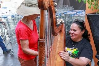 O som da harpa de Dolly atrai as pessoas que veem sua apresentação (Foto: Henrique Kawami)