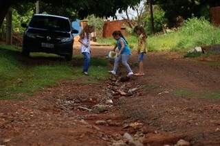 Meninas pulam erosão que avança pela Rua da Geometria, no Portal Caiobá. (Foto: André Bittar)