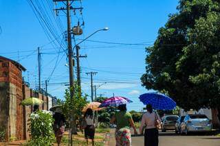 De manhã o sol é de rachar e as moradoras saem de casa com guarda-chuvas para se protegeram na rua (Foto: Henrique Kawaminami)