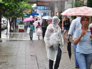 Capas e guarda-chuva foram usados para escapar da chuva esta tarde. (Foto: João Garrigó)