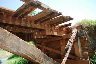 Pedaços de madeira da ponte desabaram (Foto: Ivi Notícias)
