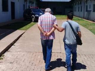 Rondon com os braços atrás sendo conduzido por policial na chegada à Polinter (Foto: Divulgação/PCMS)