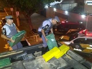 Policiais descarregam fardos de maconha encontrados em caminhão que saiu de Dourados (Foto: Divulgação)