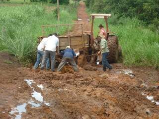 Moradores tentam desatolar trator em estrada da área rural de Coxim. (Foto: Divulgação)