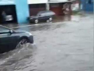 Carro passa por avenida em meio a enxurrada (Foto: Direto das Ruas)