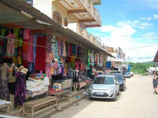Mercadorias ficam penduradas em frente as lojinhas, em meio a rua empoeirada. (Fotos: Marlon Ganassin)