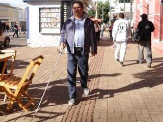 Pessoa com deficiência visual se orientando por piso tátil no Centro de Campo Grande. (Foto: Kisie Ainoã) 