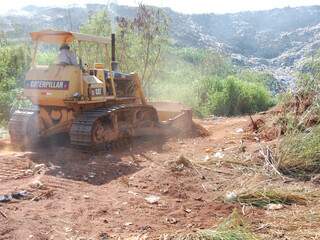 Trator leva montante de terra para barrar trabalho de catadores na região onde menino foi soterrado. (Foto: Simão Nogueira)