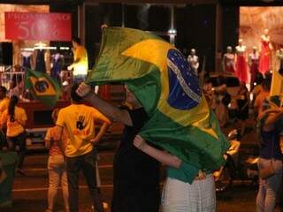 Manifestantes usam bandeira do Brasil para se proteger da chuva (Foto: Alan Nantes)