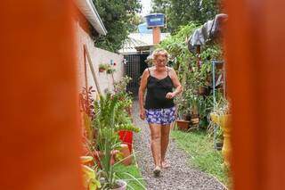 Toda simpática, ela abre a porta de casa passando pelo corredor que virou jardim. (Foto: Henrique Kawaminami)