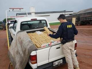 Policial retira tabletes de maconha de caminhonete apreendida em território paraguaio (Foto: Divulgação)