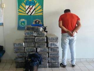 Traficante ao lado dos tabletes de droga que transportada no veículo. (Foto: Divulgação) 