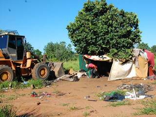 Trator derrubando barraco enquanto morador recolhe pertences (Foto: Simão Nogueira)