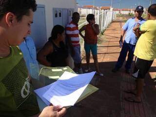 Alex Nunes mostra a papelada que confirma a posse do apartamento ao lado de outros moradores que ocupam o local desde sábado (16). (Foto: Fernando Antunes)