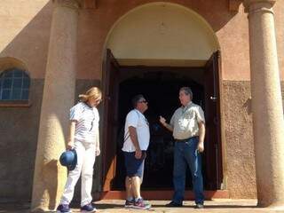 Carlos (à direita) com um casal de turistas na porta da igreja Nossa Senhora do Perpétuo Socorro (Fotos: Arquivo pessoal)