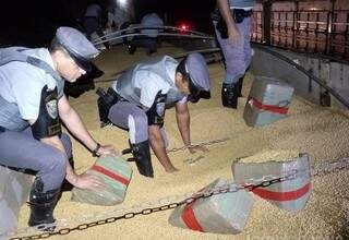 Policiais retiram fardos de maconha da carga de soja (Foto: Divulgação)