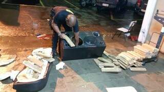 Policial do DOF retira tabletes de maconha da caixa de som de carro apreendido ontem em Dourados (Foto: Divulgação/DOF)