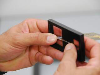 Policial explica a forma como os dispositivos prendiam os cartões nos caixas eletrônicos (Foto: Rodrigo Pazinato)