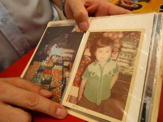 Ele mostra uma de suas fotos, ainda criança, na frente da banca da mãe. (Foto: André Bittar)