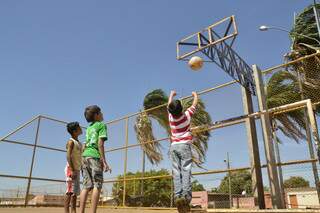 Crianças brincam mesmo sem a tabela de basquete.