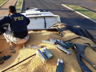 PRF em cima de caminhão carregado com grãos de milho e carteiras de cigarro contrabandeadas (Foto: Divulgação/PRF)