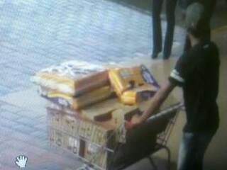 Suspeitos saindo do supermercado com carrinho cheio de mercadorias furtadas.