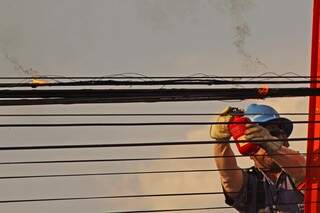 Operário apaga fogo em fio: calor está insuportável em Campo Grande (Foto: Marcos Ermínio)