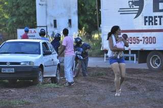 Com criança no colo, mulher se afasta de local após ouvir tiros; famílias foram repelidas à bala ao tentarem invadir área no Distrito Industrial (Foto: Eliel Oliveira)