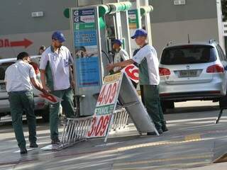 Funcionários trocando placas com novo preço da gasolina (Foto: Saul Schramm)