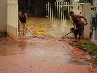 Moradores retiram água de entrada de casa no Marcos Roberto. (Foto: Rodrigo Pazinato)