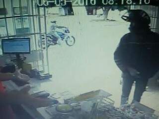 Imagens de segurança mostram homem armado assaltando loja. (Foto: Reprodução)
