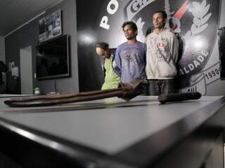 Faca e facão usados no crime e ao fundo, os suspeitos. Da esquerda para direita: Rivelino, Rogério e Alerto. (Foto: João Paulo Gonçalves) 