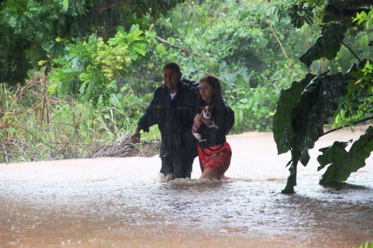 Moradora é ajudada a sair de casa após chuvas tomarem ruas de Bonito