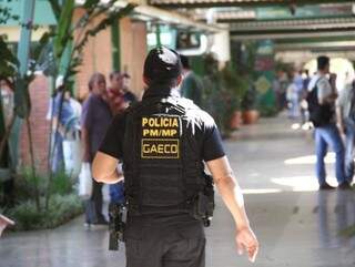 Policial em cumprimento de mandado de prisão, busca e apreensão no Detran (Foto: Marcos Ermínio) 