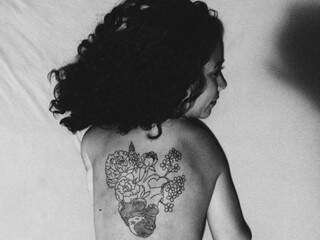 Tatuagem no nas costas, com o coração e as flores que marcam a vida de Sarah.