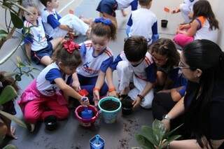 Crianças colocando a mão na terra, para aprender educação ambiental. (Foto: Divulgação)