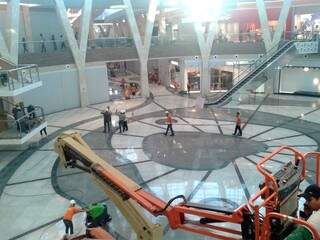 Funcionários limpam a praça central do shopping.