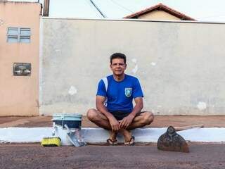 Após limpar e pintar, José Carlos de Oliveira na calçada da rua para descansar  (Foto: Henrique Kawaminami)