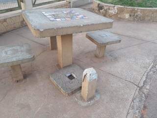 Um dos bancos da mesa de concreto está no chão no Elias Gadia. (Foto: Direto das Ruas).