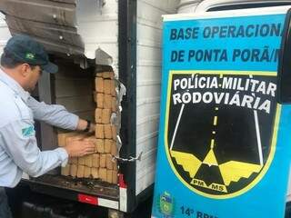 Policial retira maconha de fundo falso de caminhão-baú, apreendido de madrugada em Ponta Porã (Foto: Divulgação)
